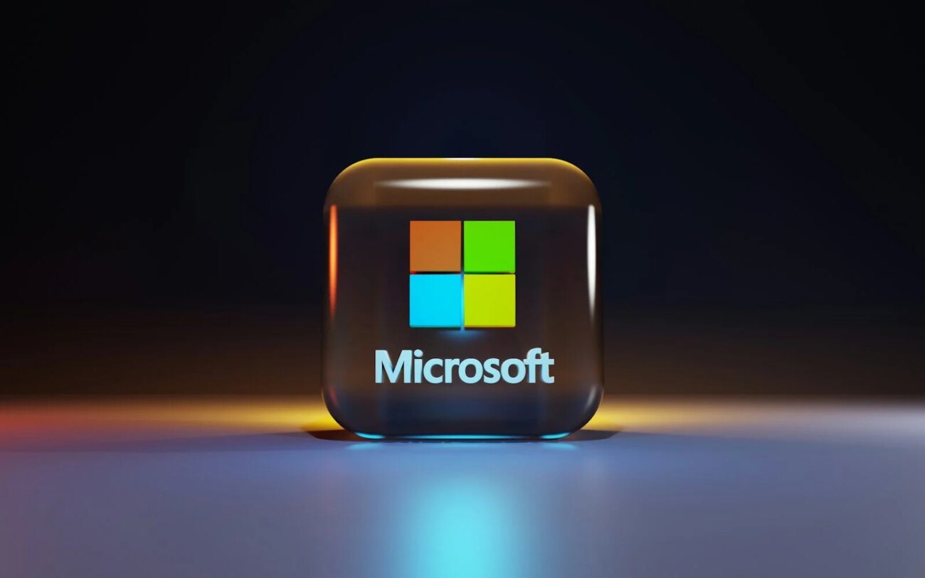A glossy glass cube with the Microsoft logo on a dark surface