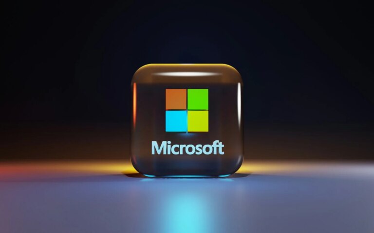 A glossy glass cube with the Microsoft logo on a dark surface